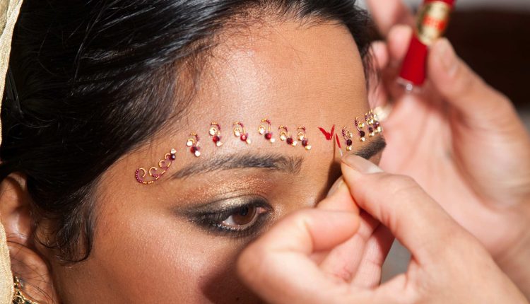 A bindi is a mark worn on the forehead, traditionally placed between the eyebrows. The word comes from the Sanskrit bindu, meaning “point” or “drop.”
