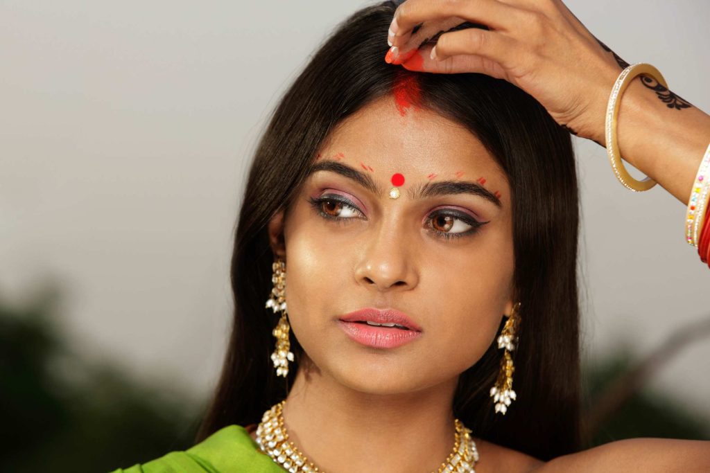 A red bindi, worn by married women, became both a personal and social marker—subtle, yet widely understood. It often appeared alongside other symbols such as sindoor, the red powder applied along the hair parting.