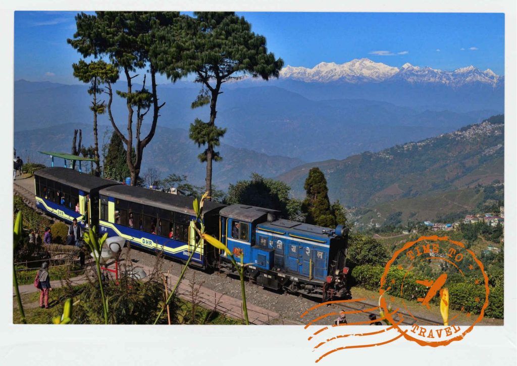 Before sunrise, Kanchenjunga appears as a deep blue silhouette against the night sky. Then comes silver, rose, and finally gold as the first rays touch the mountain. Below, tea gardens shimmer emerald beneath drifting mist, while monasteries add flashes of saffron and crimson to the hillsides.
