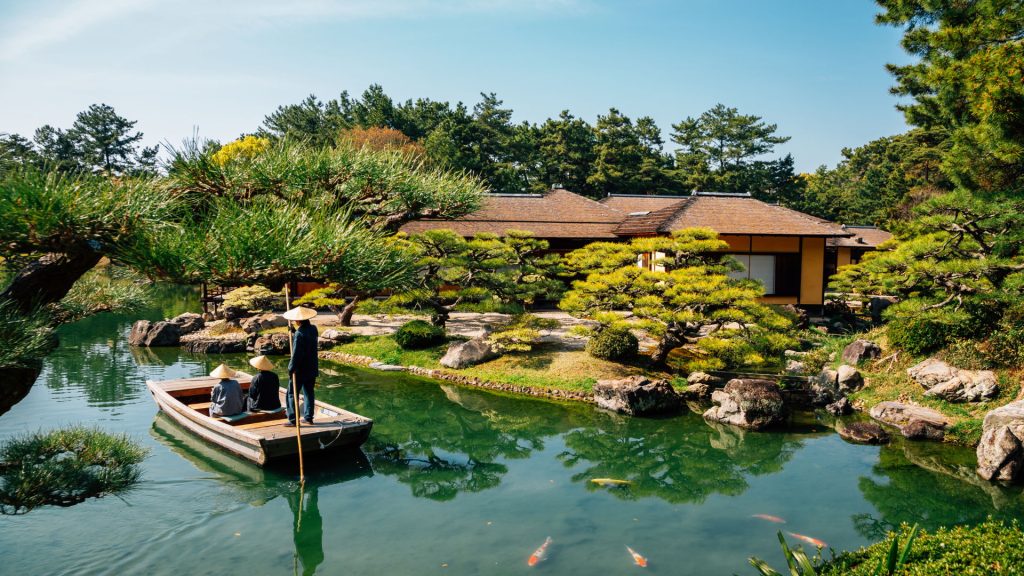 A traditional Japanese garden featuring a serene pond with koi fish, manicured pine trees, a wooden boat carrying passengers, and a classic tea house in the background.